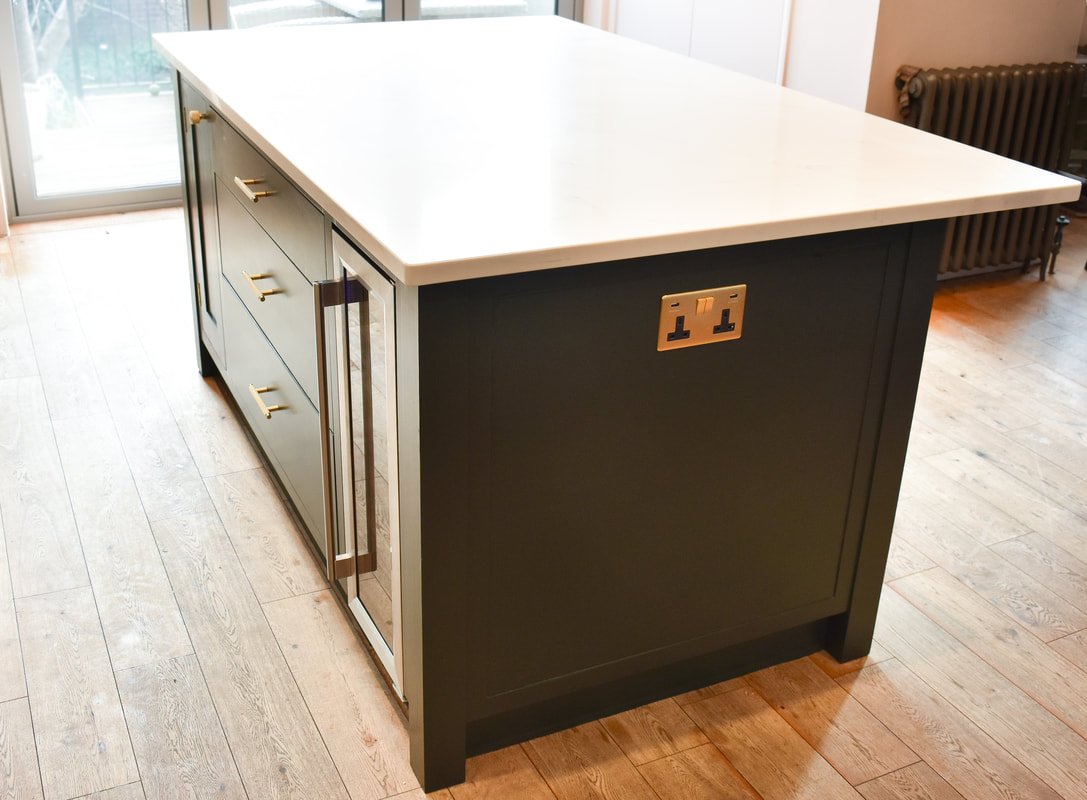 An elegant handmade bespoke kitchen island with panelled doors an integrated  wine fridge, drawers, designed made and fitted in Highgate North London