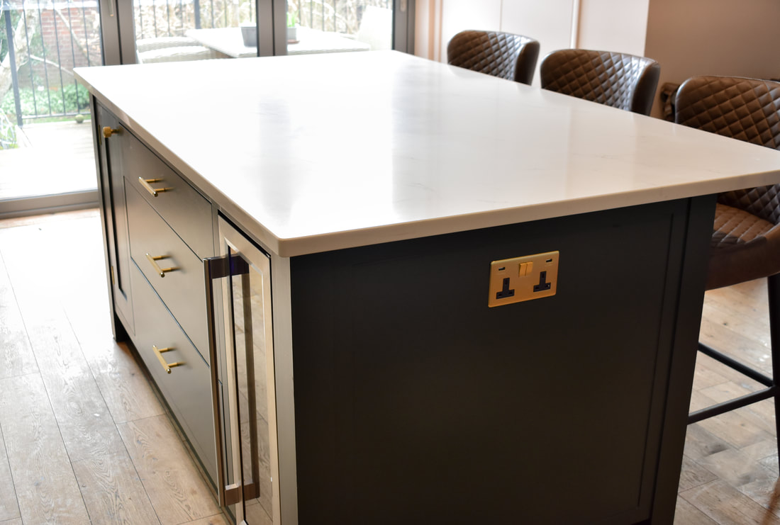 An elegant handmade bespoke kitchen island with panelled doors an integrated  wine fridge, drawers, designed made and fitted in Highgate North London