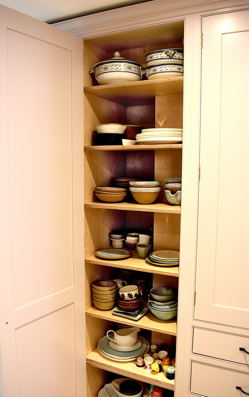 Interior view of birch ply shelving in a tall cabinet in a framed kitchen North London