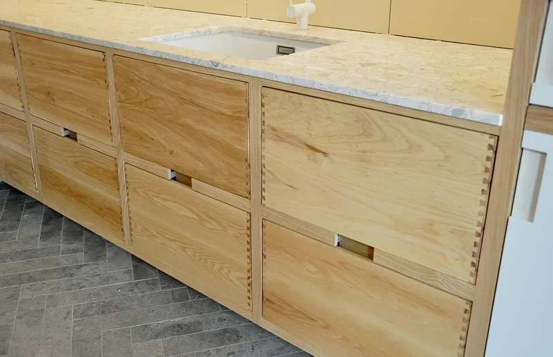 Drawer details on solid ash kitchen in Dulwich London with dovetailed details on drawer fronts. Fluted ash kitchen island with birch ply drawers 