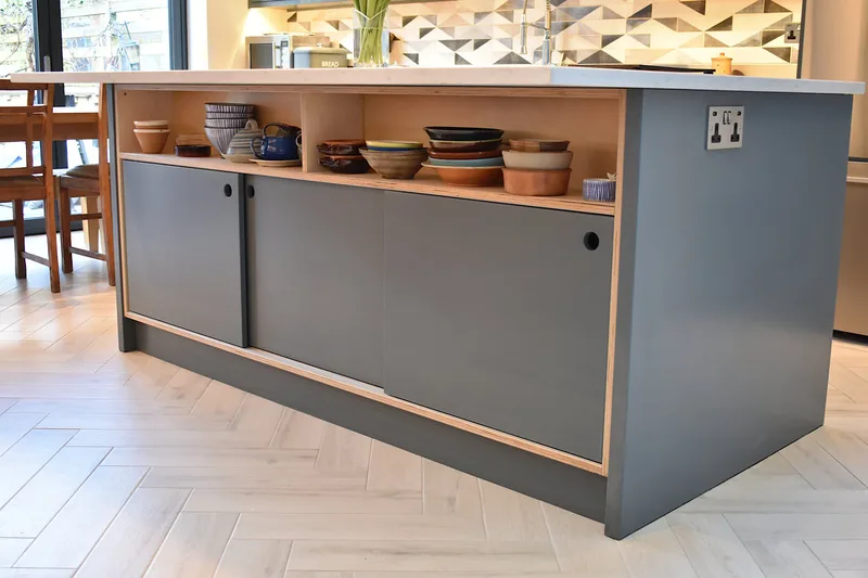 Contemporary mixed materials kitchen in Stroud Green North London finish sprayed with recessed drawer pulls and kitchen island with sliding doors 