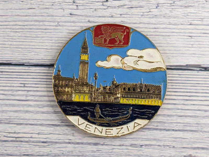 A Venezia magnet from Italy, circular in shape with an image of Venice with gilded accents.