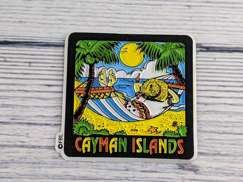 A refrigerator magnet with an embossed design image of a hammock at the beach with the words Cayman Islands.