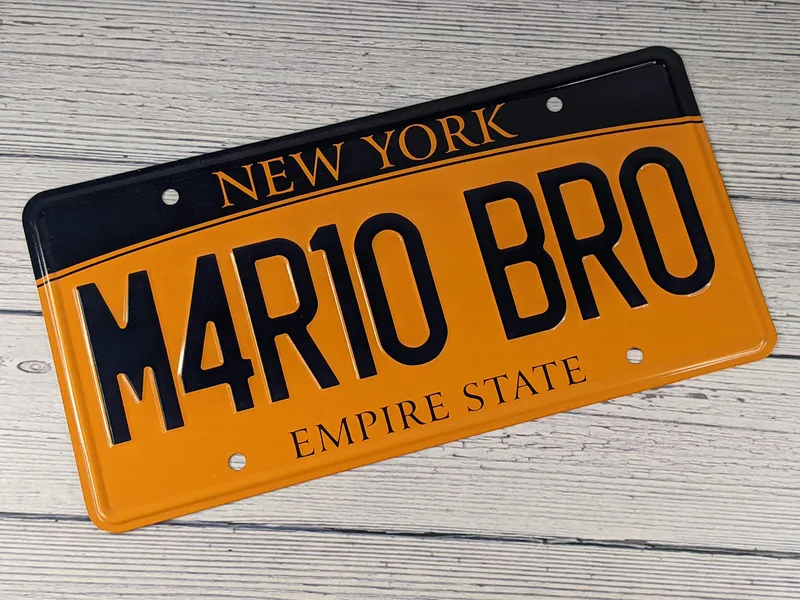 An orange and navy blue replica New York license plate as shown in the movie Super Mario Bros. It reads M4R1O BRO.