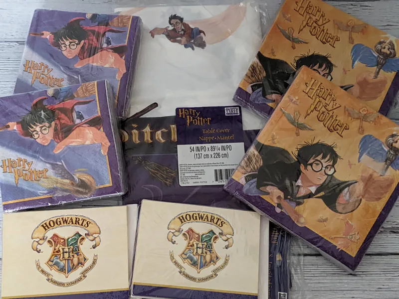 A Harry Potter party set of napkins, a tablecloth, and invitations, all with images of the Harry Potter character or Hogwarts logo.