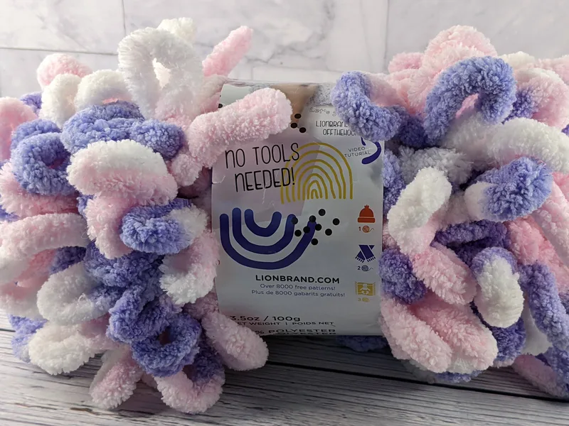 A skein of Off The Hook yarn by Lion Brand in Unicorn (pink, purple, white).