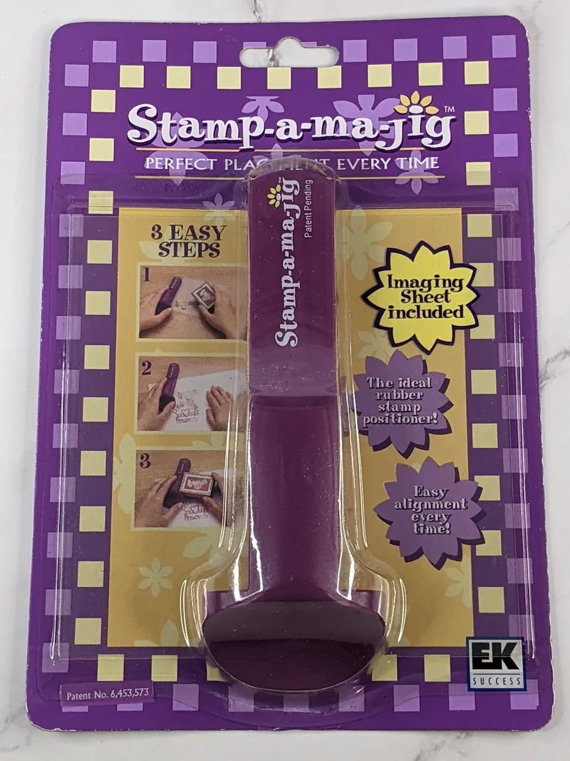 A new product package containing a purple stamp-a-ma-jig stamping tool with an imaging sheet.