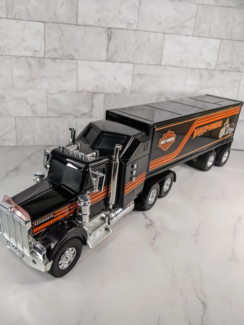 An Empire Kenworth Harley Davison semi-truck toy with lights and sounds, vintage from 1996, black and orange.