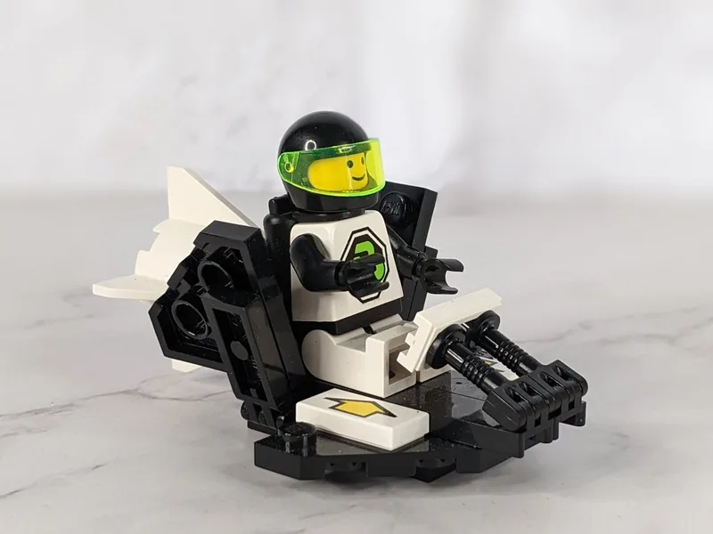 A vintage 1992 Lego figure, Blacktron 2 Galactic Scout 1426 1694 that is in a black and white space rocketship.