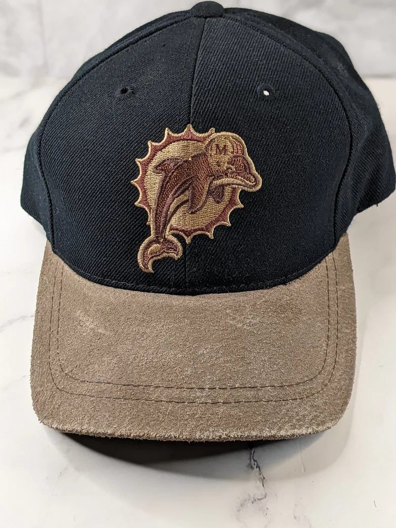 A black baseball-style cap with a tan bill and the vintage/retro NFL Miami Dolphins logo.