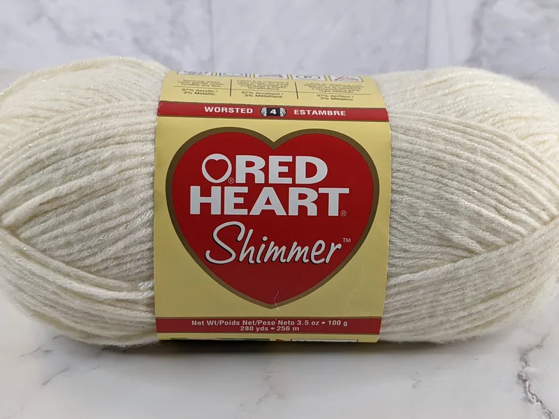 An ivory-colored skein of yarn with shimmer flecks made by Red Heart.