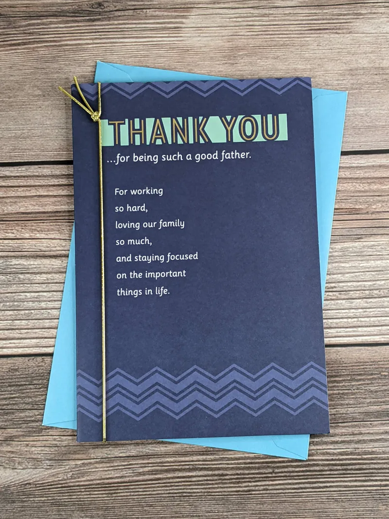 A navy-blue greeting card for a husband on Father's Day, featuring a gold elastic cord decoration.