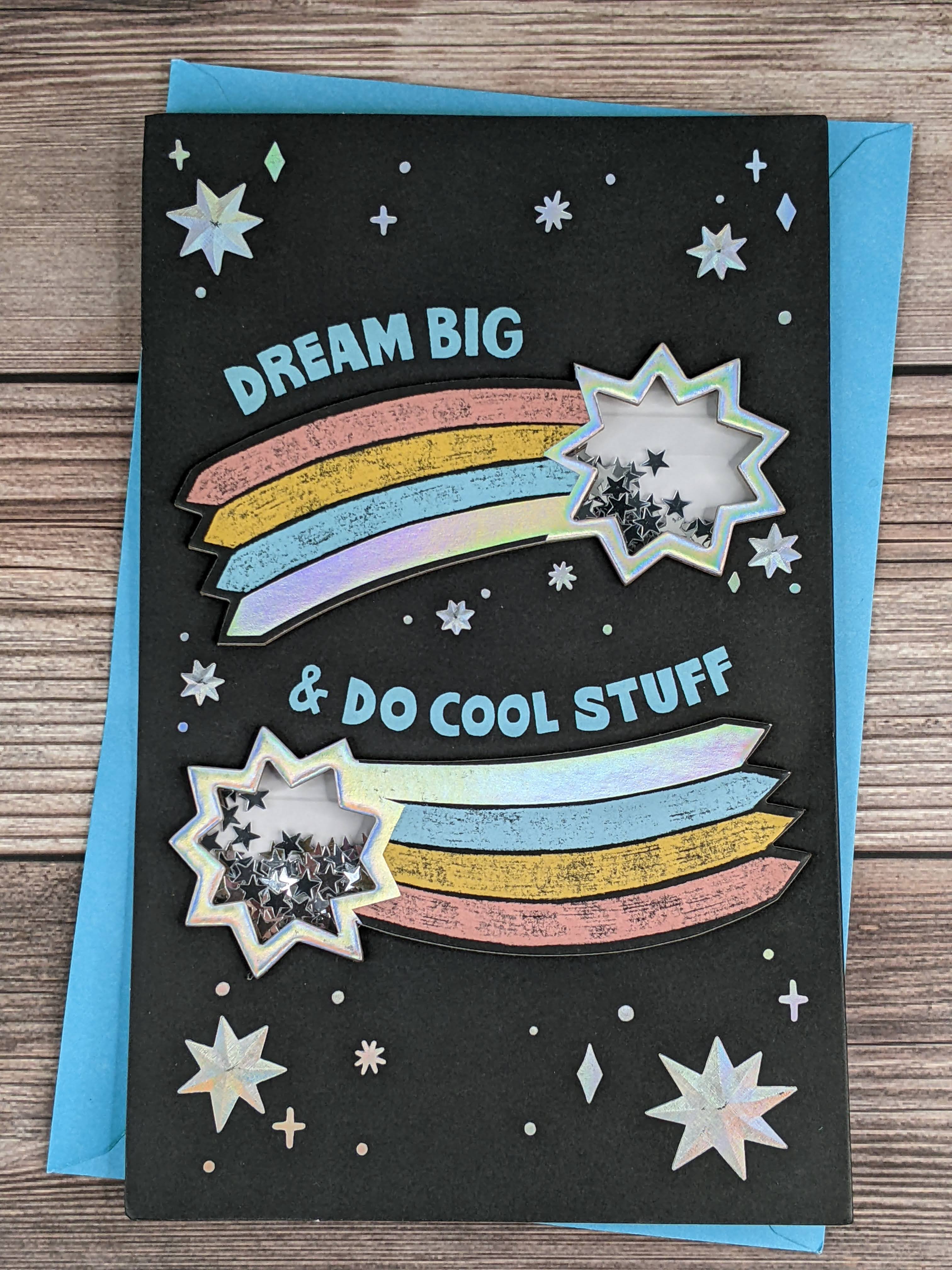 A graduation card with a black cover, a design with dimensional shooting stars that contain shakable confetti of silver stars.