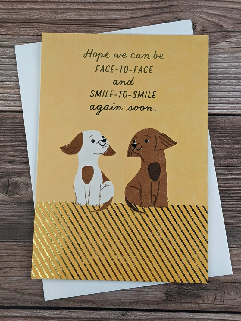 A missing you greeting card by Hallmark with a yellow front that has an image of two dogs looking at each other.