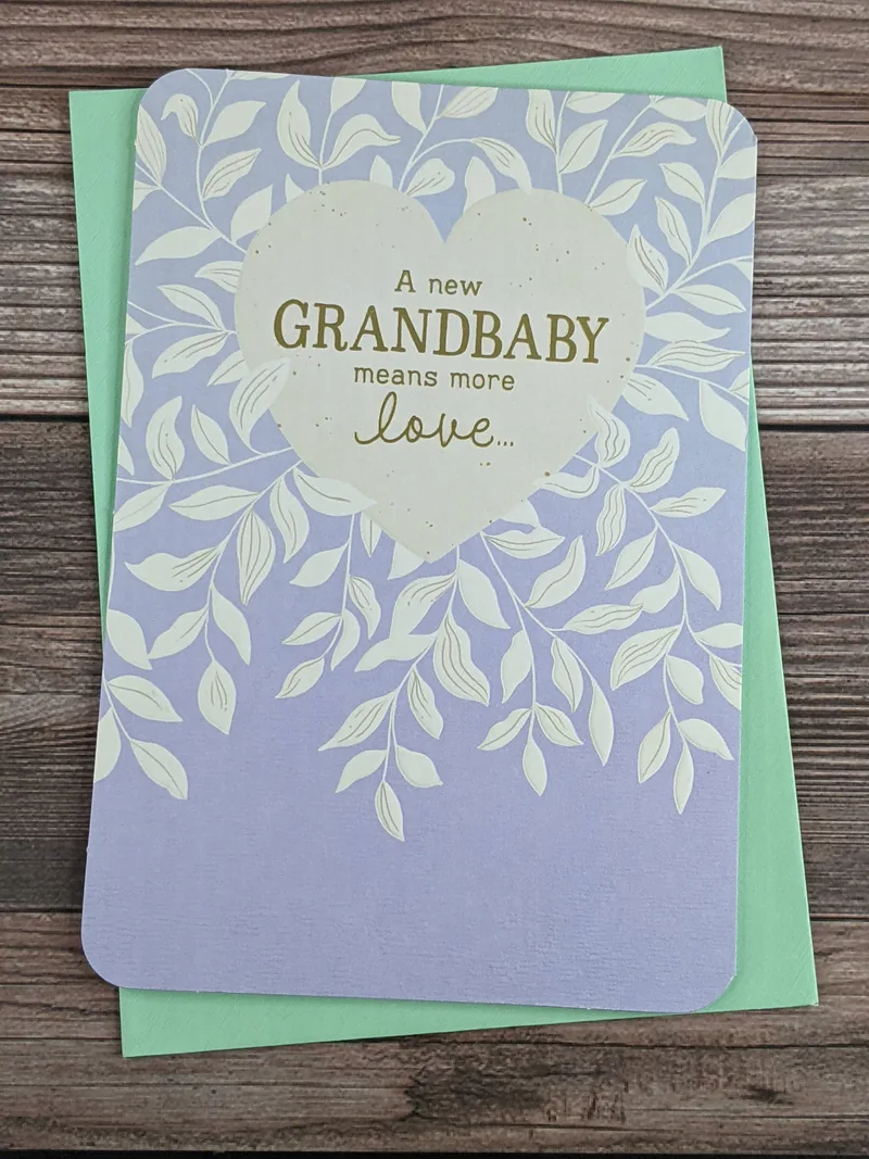 A greeting card to congratulate grandparents on the birth of a grandchild. It has a lavender cover with a white heart and leaves.