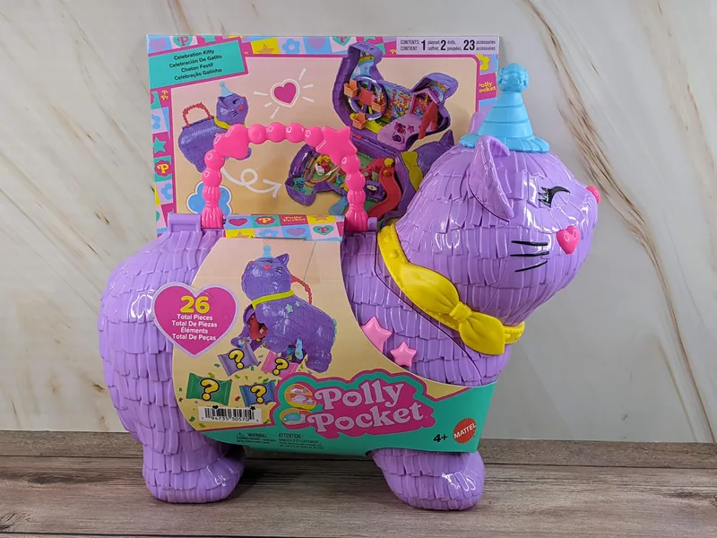 A purple plastic cat-shaped carrying case with a set of Polly Pocket toys inside.