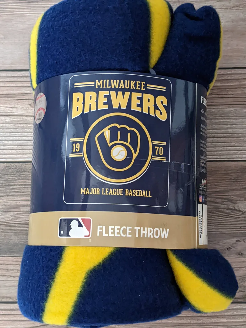 A yellow, blue, and white fleece throw blanket featuring MLB Milwaukee Brewer's retro ball and glove logo.