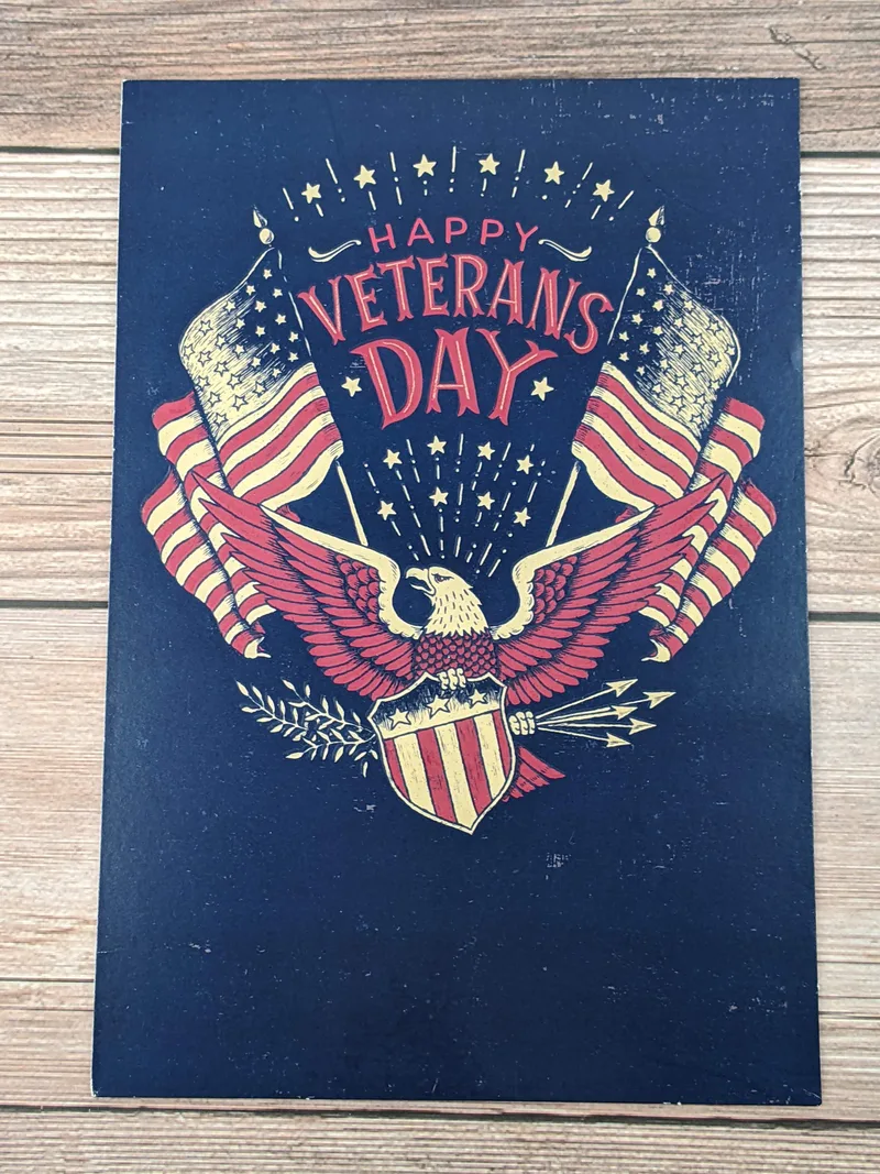 A Veterans Day card with an image of an eagle with a shield and two American flags.