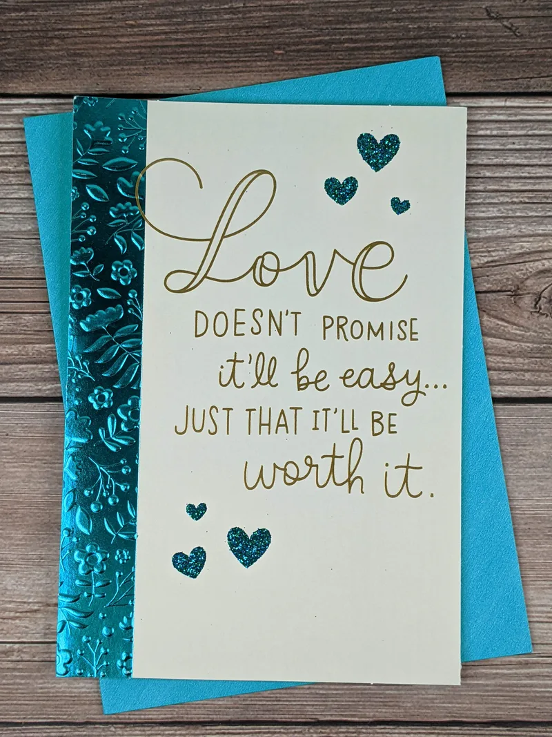 A glittery metallic greeting card for "Our Anniversary" with images of hearts and embossed flowers.