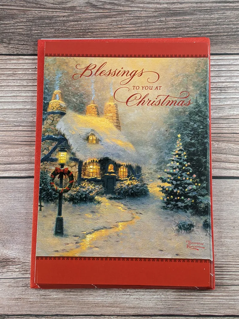 A pile of Hallmark Christmas cards by Thomas Kinkade with artwork of a snowy scene on the cover.