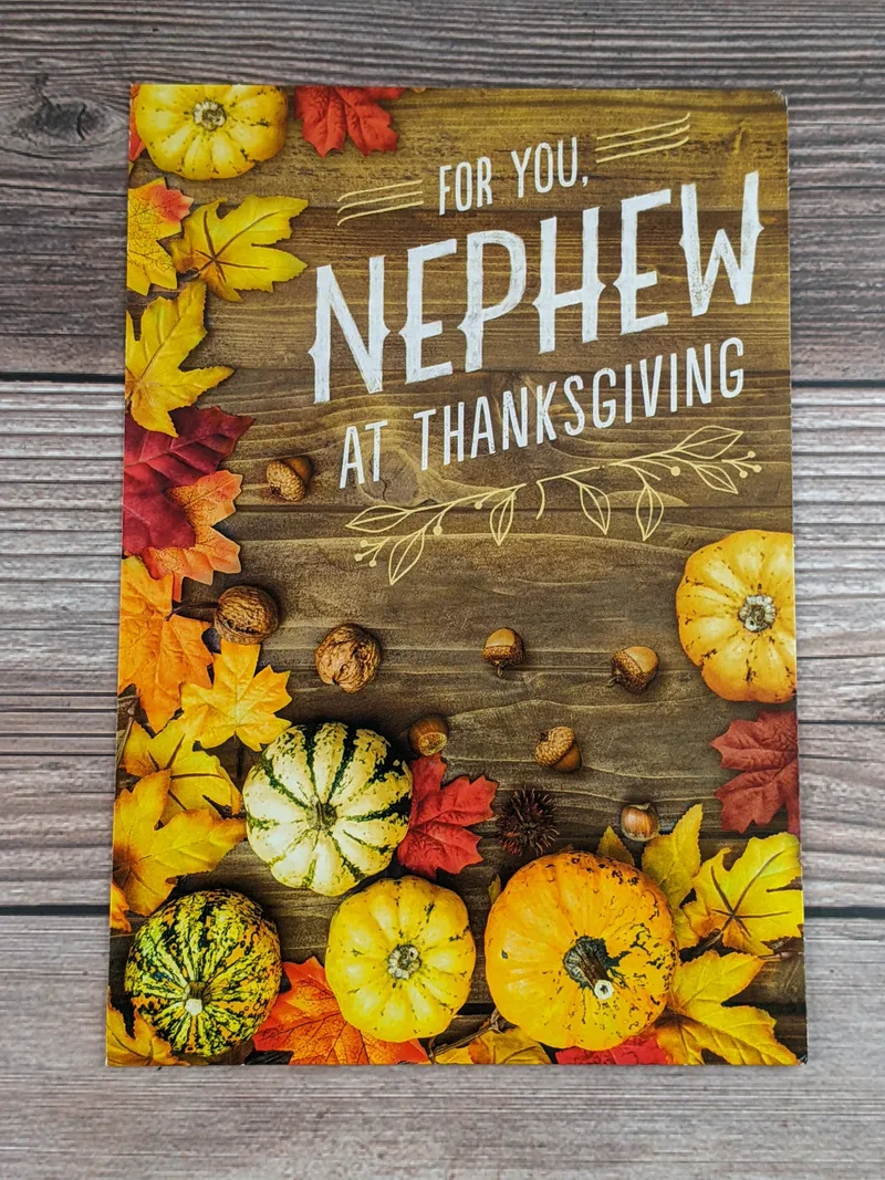 A nephew thanksgiving card with an image of leaves and pumpkins on wood.