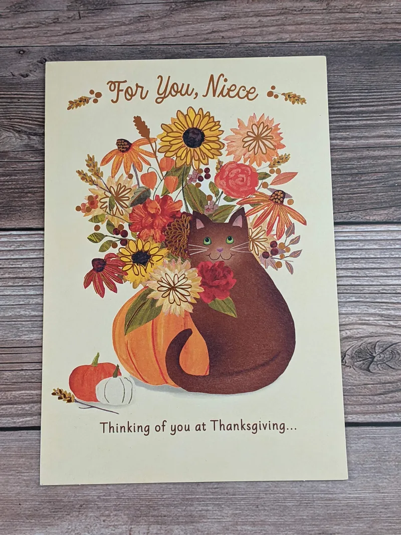 A thanksgiving card for a niece with an image of a cat near a pumpkin with flowers.