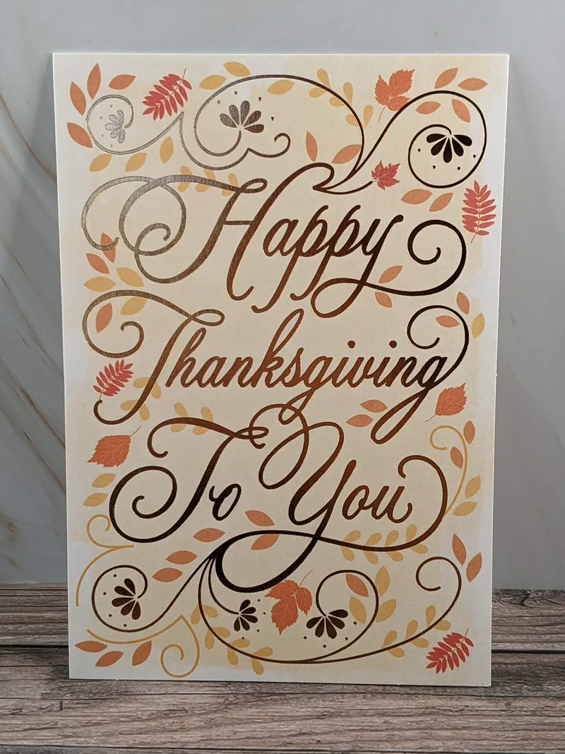 A Thanksgiving card with metallic lettering and images of swirls and leaves.