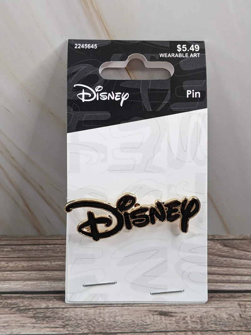 A collectible metal lapel pin with black enamel lettering, spelling out "Disney" in a logo format.