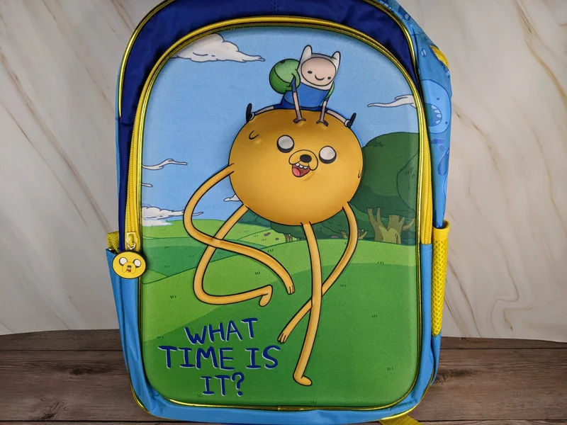 A yellow and blue Adventure Time backpack featuring a dimensional image of Cartoon Network characters.
