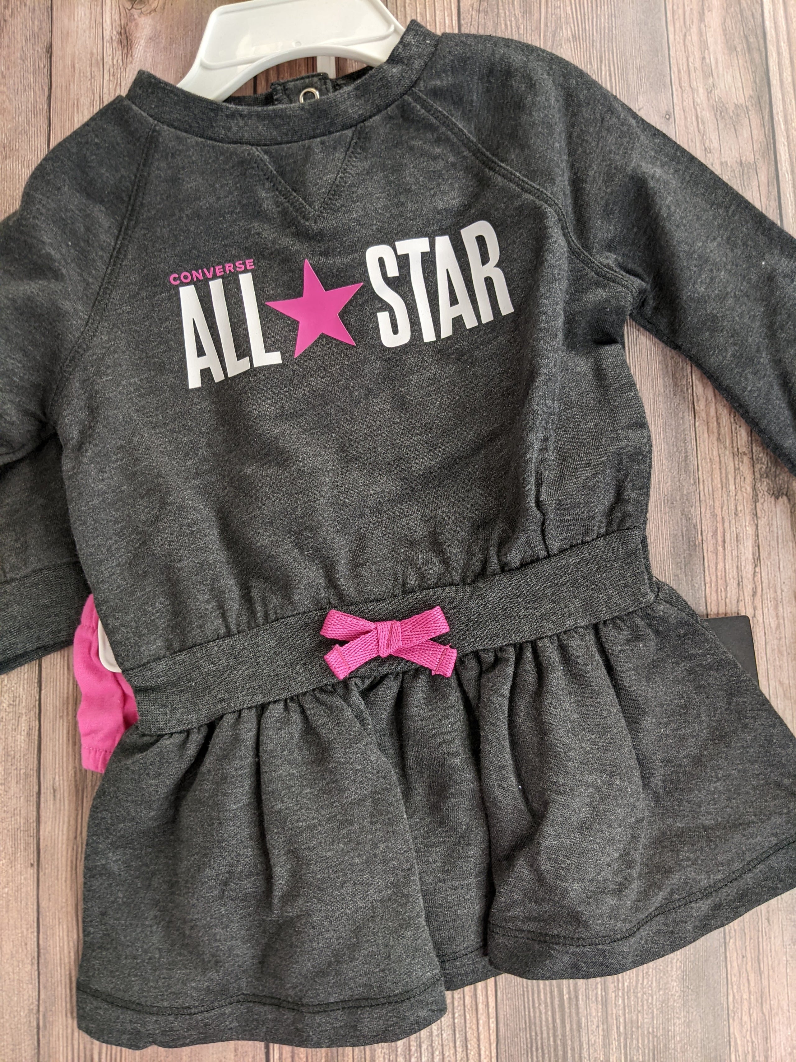 A dark gray ruffle romper for a baby girl, with an all-star design by Converse. 