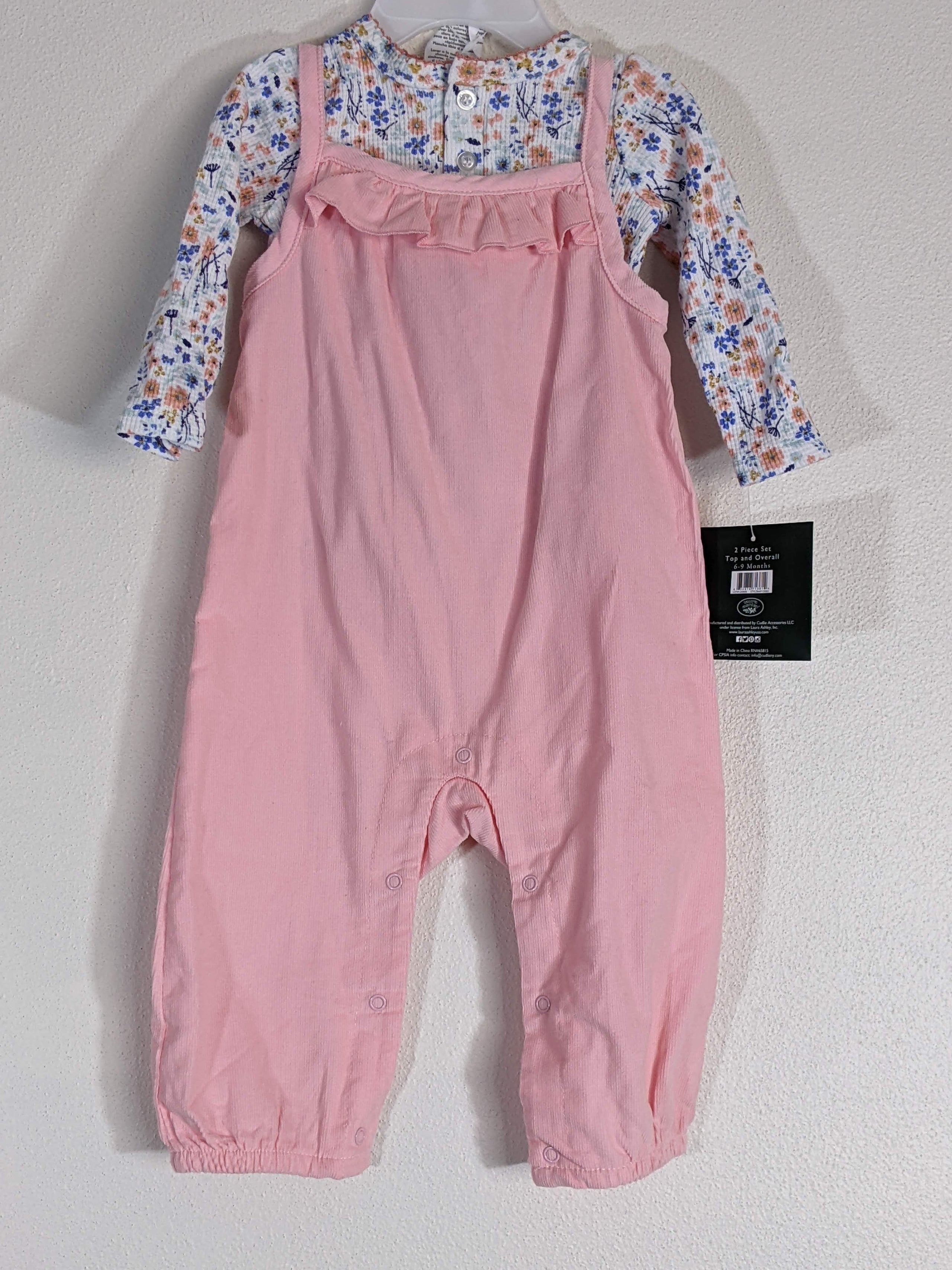 A pink overall infant outfit with a flower undershirt.