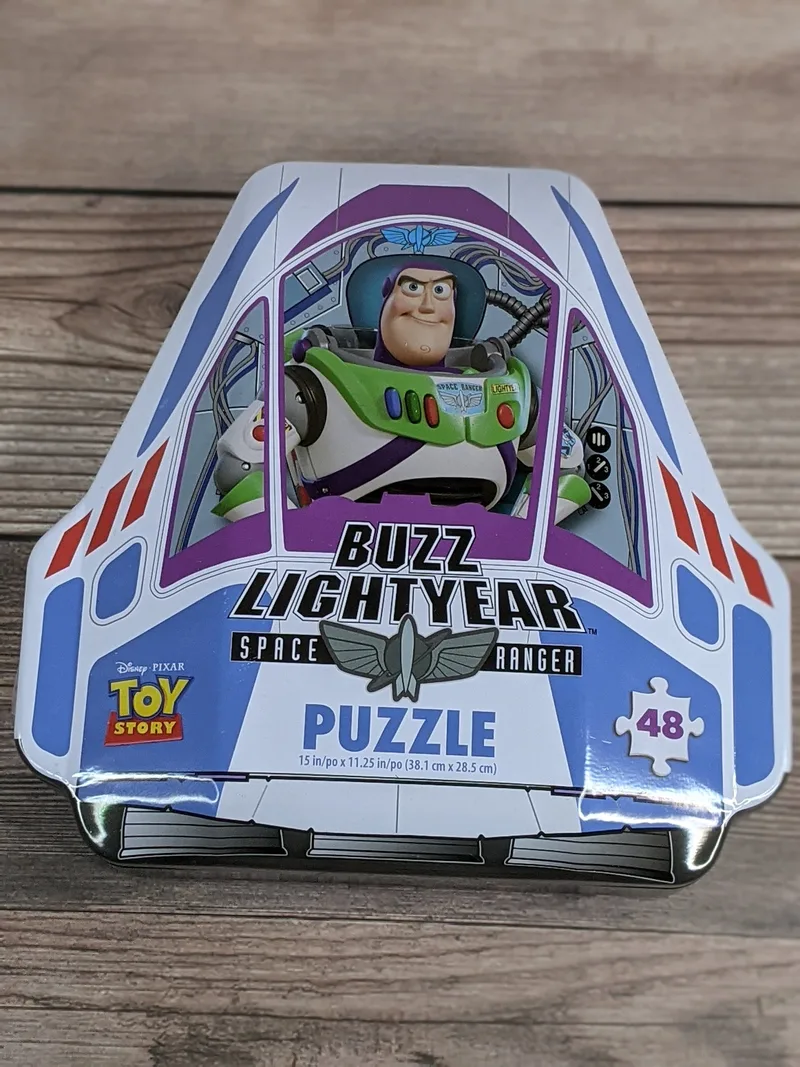 A metal tin shaped like a rocket with an image of Disney's Toy Story Buzz Lightyear, that includes a puzzle inside.
