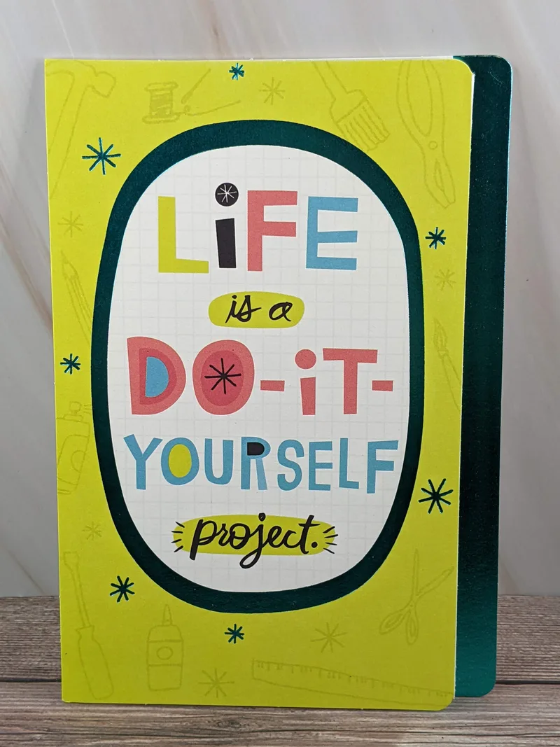 A birthday card with a sentiment on the front yellow cover that describes life as being a do-it-yourself project.