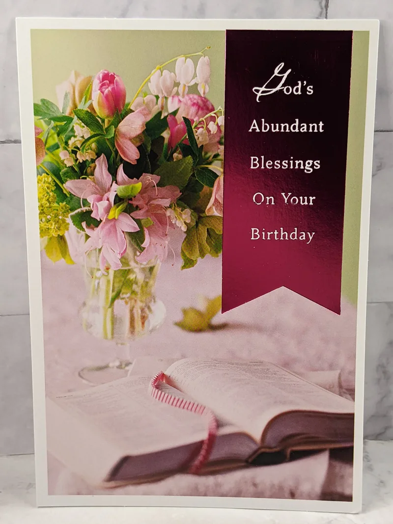 A religious birthday card for a woman, with an image of a vase of flowers next to an opened Bible.