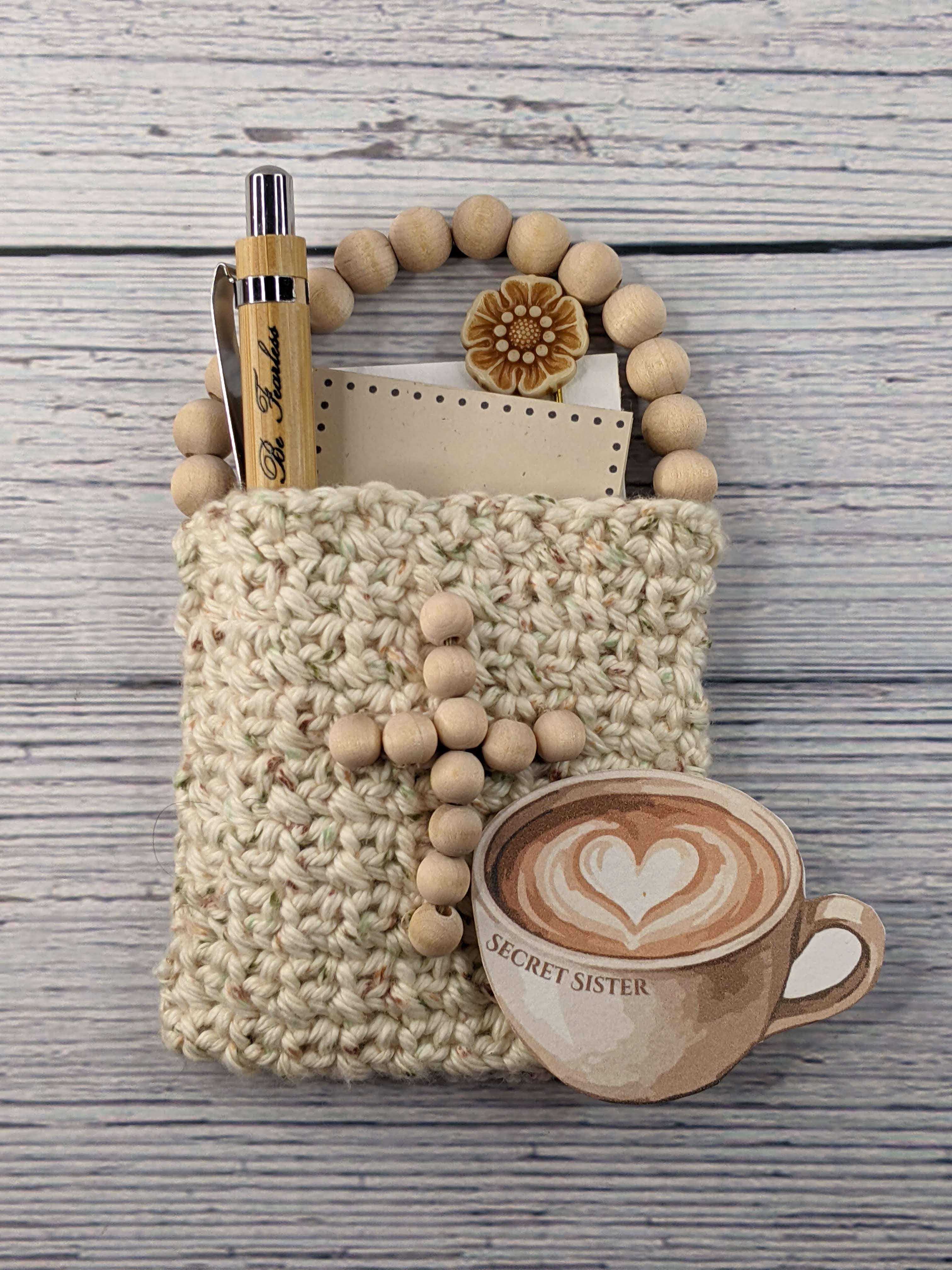 A crocheted gift bag with Christian items in it with a Secret Sister gift tag.