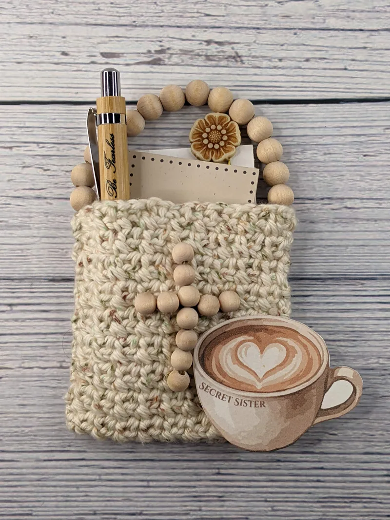 A crocheted gift bag with Christian items in it with a Secret Sister gift tag.