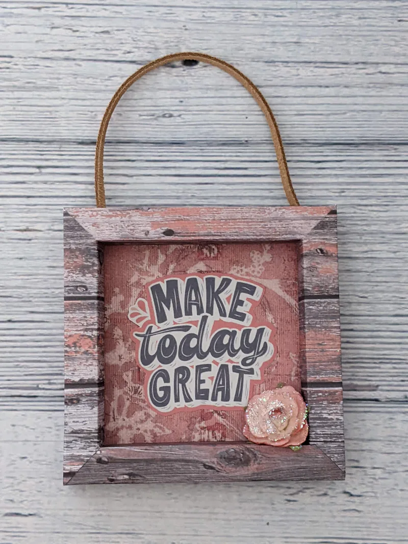 A wall sign with a pink glitter flower and the words "Make Today Great."