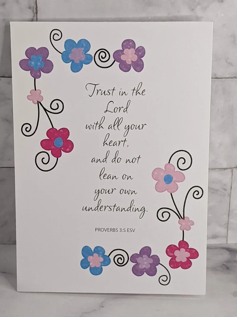 A religious greeting card with a Trust in the Lord Bible verse, and a design of pink, purple and blue flowers.