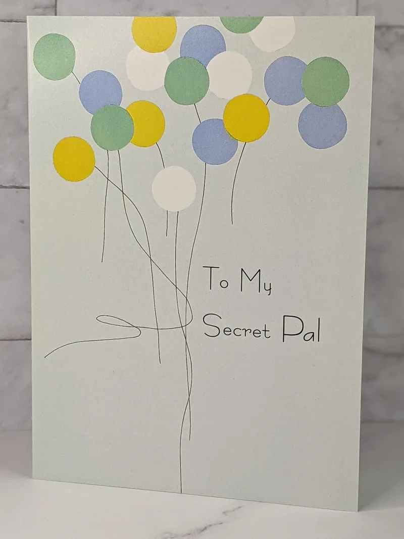 A religious birthday greeting card for a Secret Pal with a blue cover and a design of yellow, green and blue balloons.