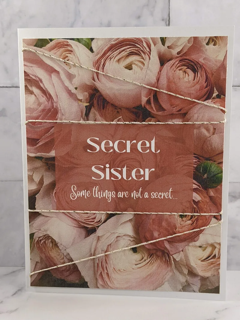 A greeting card for a Secret Sister with an image of pink flowers on the cover and a message of friendship.