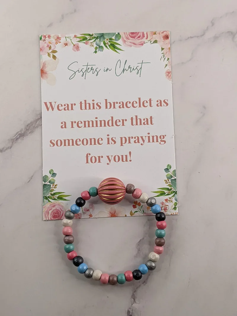 A pink and blue beaded bracelet with a tag referring to Sisters in Christ, a gift idea for a Secret Sister