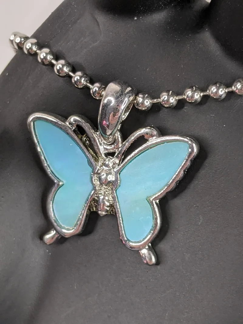 A blue Mother of Pearl pendant shaped like a butterfly on a silver ball-chain necklace.