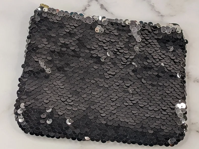 A small pouch with black sequins that are silver when flipped.