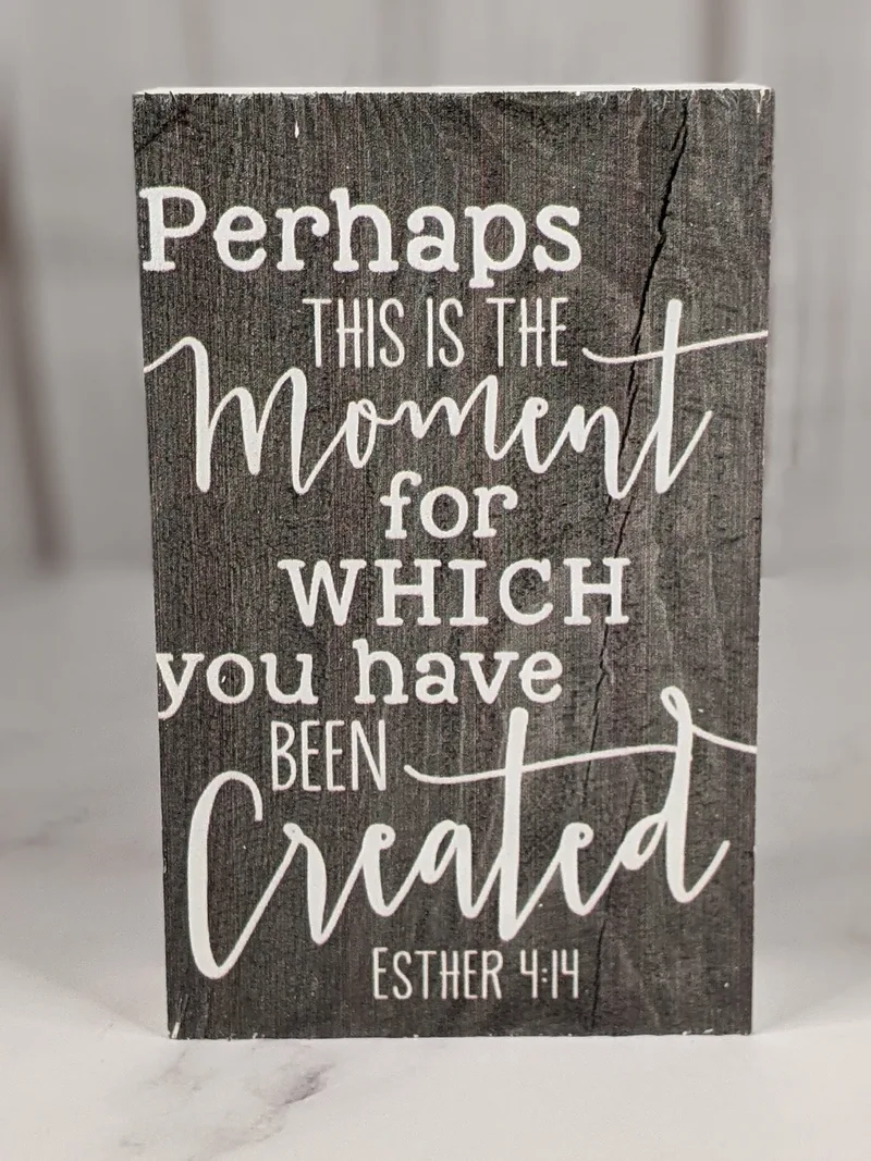 A black sign to sit on a shelf with a Scripture, "Perhaps this is the moment for which you have been created. Esther 4:14."