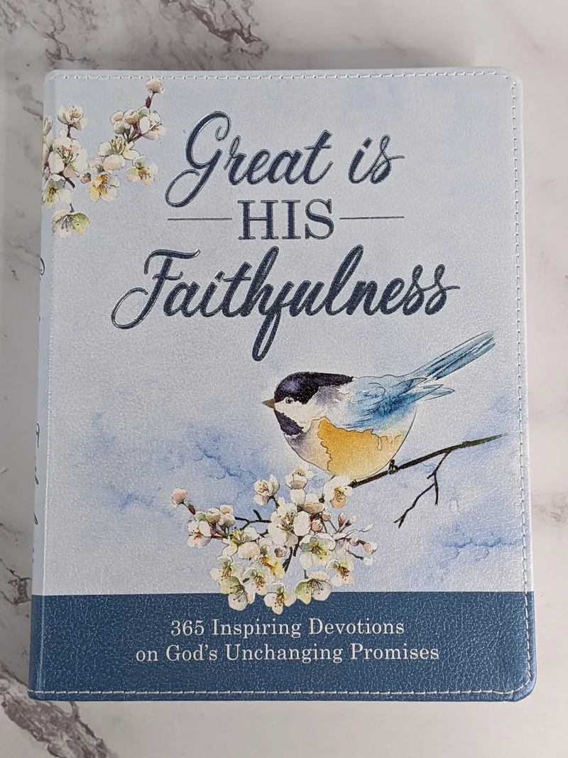 A leather-like light blue devotional book with a bird and flower design on the cover, that features religious devotions.