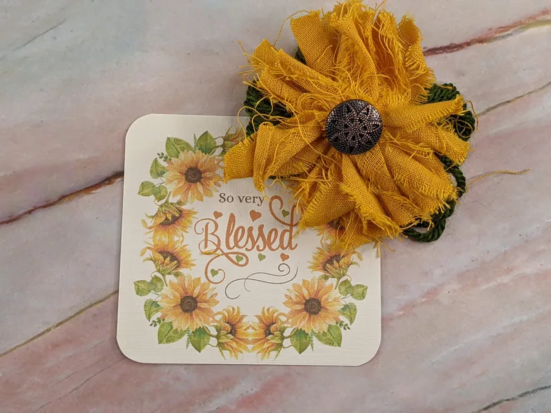A shabby fabric sunflower with a "so very blessed" product tag.