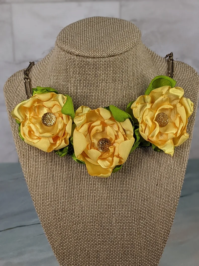 Beautiful yellow handmade satin flowers are featured on this large link chain necklace in antique gold.