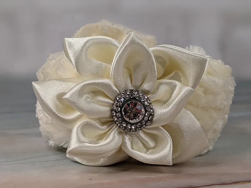 This cuff bracelet is hand-crocheted with thick plush cream/off-white velvet yarn, tied back with lace, and displays a satin flower (centered with gorgeous rhinestones), all in pretty cream tones.