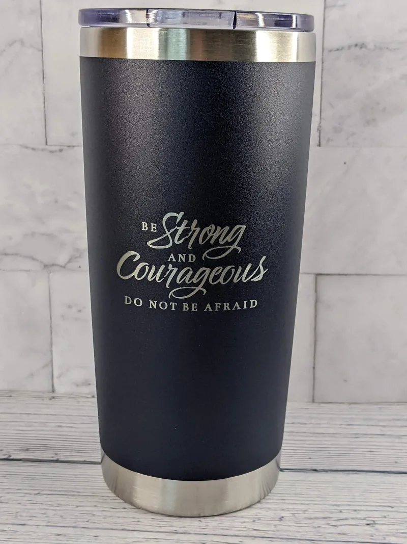 A stainless-steel travel mug with a blue exterior, featuring a Bible verse: Be strong and courageous.