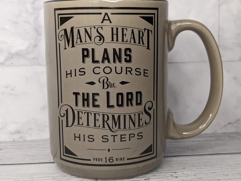 A religious mug for a man with a Bible verse. This coffee mug is tan with a black interior.